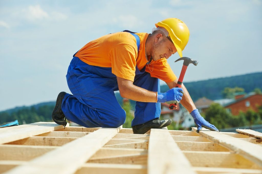 carpenter using framing hammer, one of the tools to build a shed